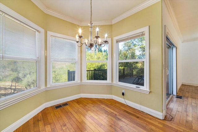 unfurnished dining area with an inviting chandelier, crown molding, and hardwood / wood-style flooring