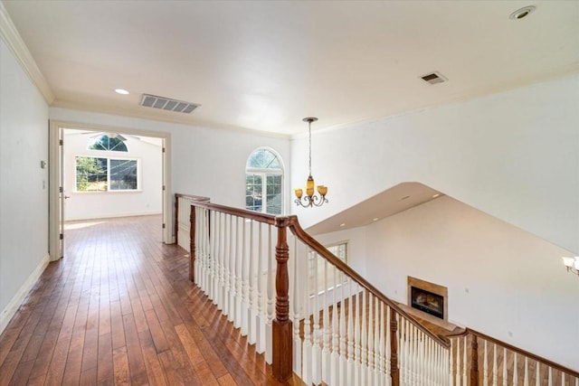 hall featuring plenty of natural light, wood-type flooring, crown molding, and a chandelier