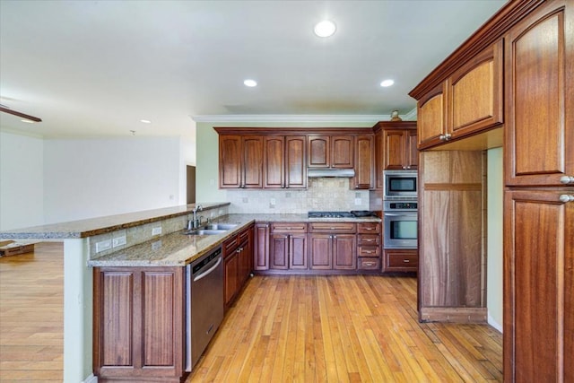 kitchen featuring kitchen peninsula, decorative backsplash, sink, appliances with stainless steel finishes, and light stone counters