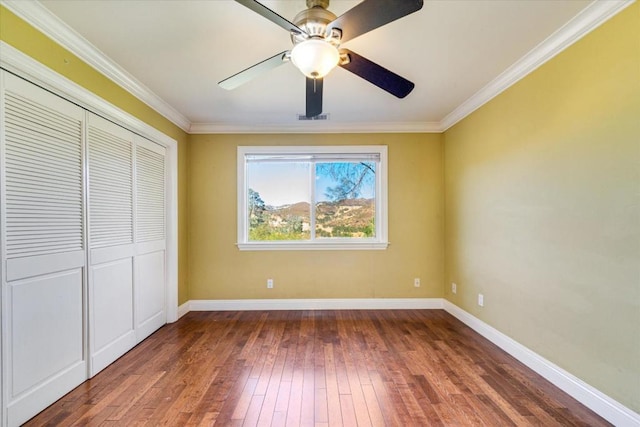 unfurnished bedroom featuring ceiling fan, a closet, dark hardwood / wood-style floors, and ornamental molding