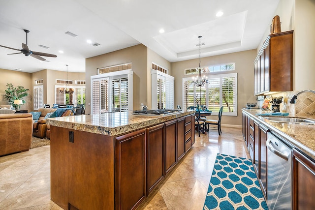 kitchen featuring a kitchen island, stainless steel appliances, sink, hanging light fixtures, and a raised ceiling