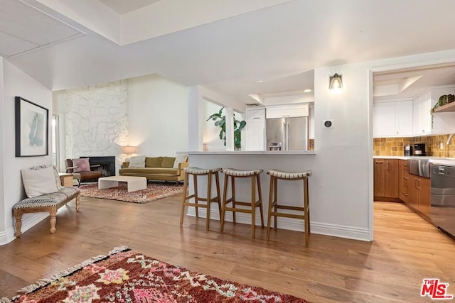 living room featuring light hardwood / wood-style flooring and a stone fireplace