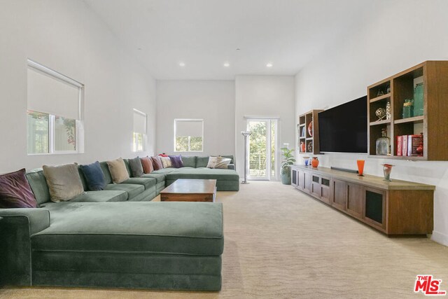 living room with light carpet and a high ceiling