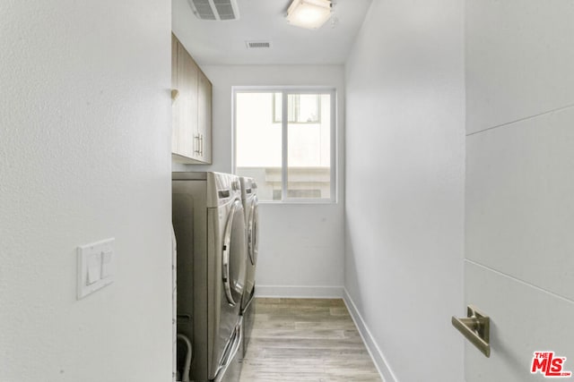 washroom with cabinets, light hardwood / wood-style flooring, and washing machine and dryer