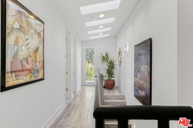 corridor featuring vaulted ceiling with skylight and hardwood / wood-style floors