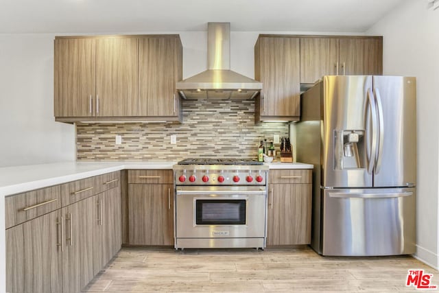 kitchen featuring light wood-type flooring, backsplash, wall chimney exhaust hood, and stainless steel appliances