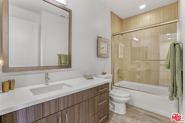 full bathroom with toilet, vanity, and shower / bath combination with glass door