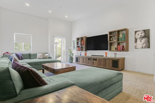 living room featuring light colored carpet and a towering ceiling