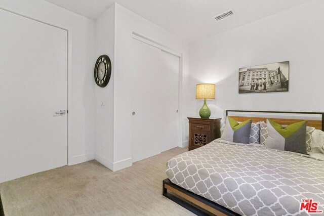 bedroom with light carpet and a closet