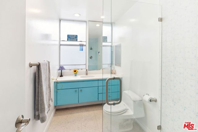 bathroom with toilet, vanity, and a shower with door