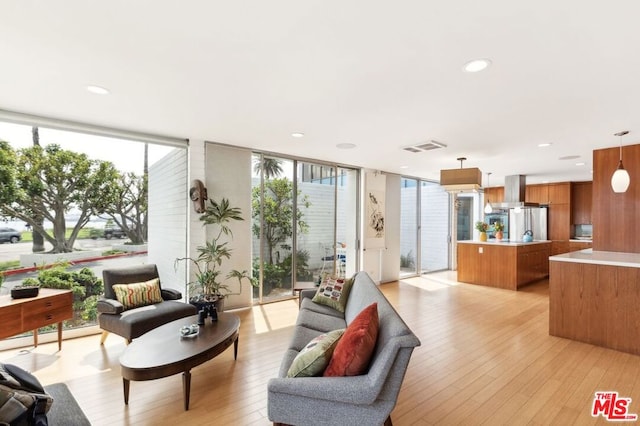 living room with light hardwood / wood-style floors, plenty of natural light, and a wall of windows