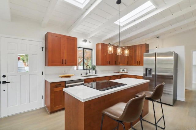 kitchen featuring a center island, a kitchen bar, stainless steel appliances, sink, and hanging light fixtures