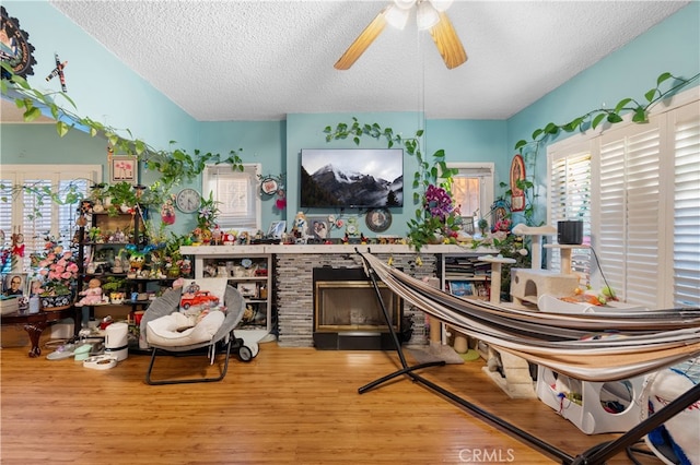 interior space with ceiling fan, light wood-type flooring, a fireplace, and a textured ceiling