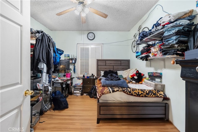 bedroom with a textured ceiling, ceiling fan, and hardwood / wood-style flooring