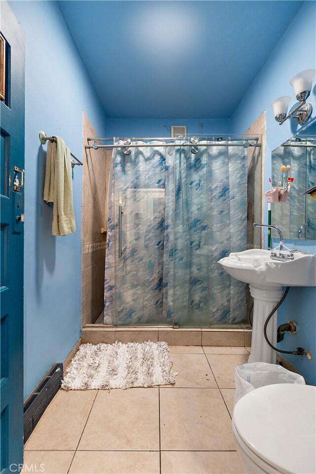 bathroom featuring toilet, tile patterned floors, and curtained shower