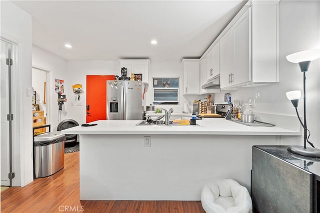 kitchen featuring range, white cabinets, stainless steel fridge with ice dispenser, and kitchen peninsula