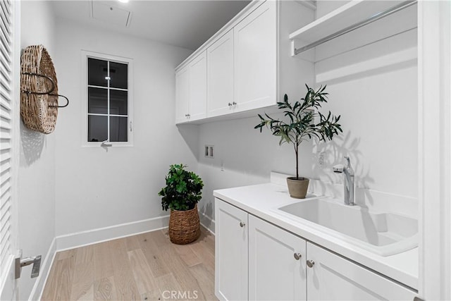 laundry room with washer hookup, cabinets, sink, and light hardwood / wood-style floors