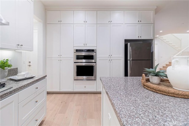 kitchen with white cabinets, appliances with stainless steel finishes, and light wood-type flooring