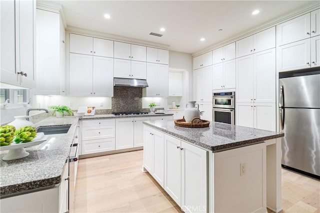 kitchen featuring appliances with stainless steel finishes, sink, white cabinets, and a center island