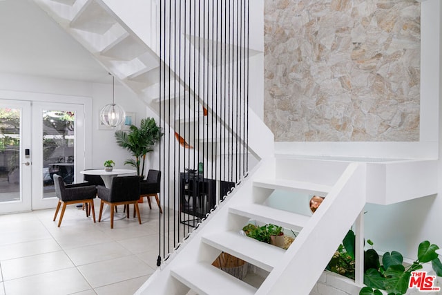 stairs featuring tile patterned flooring, french doors, and a notable chandelier