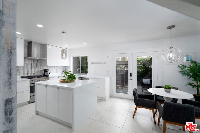 kitchen with wall chimney exhaust hood, a kitchen island, white cabinetry, hanging light fixtures, and high end stainless steel range oven