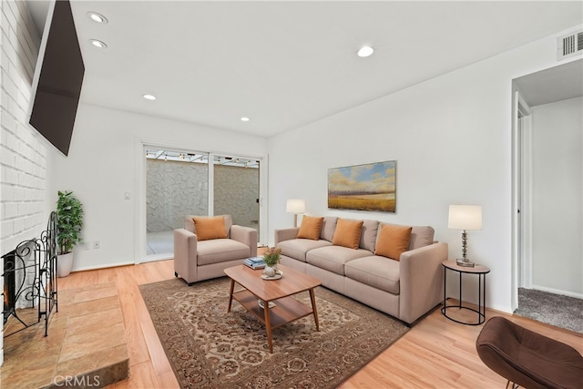 living room featuring a brick fireplace and hardwood / wood-style flooring