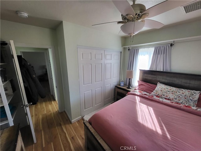 bedroom with ceiling fan, wood-type flooring, and a closet