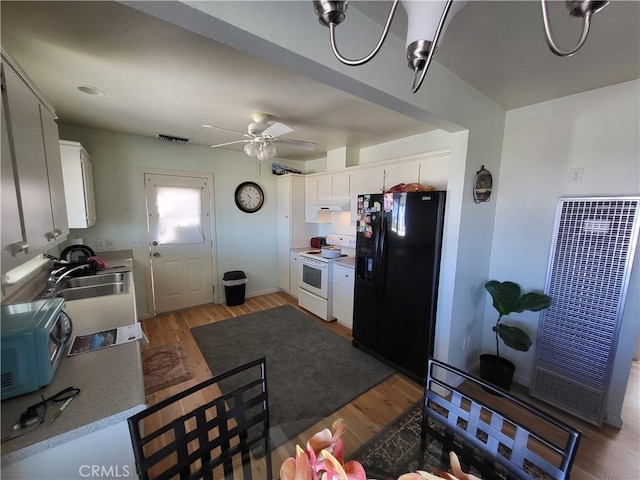 kitchen with dark wood-type flooring, white electric range oven, sink, black fridge, and white cabinetry