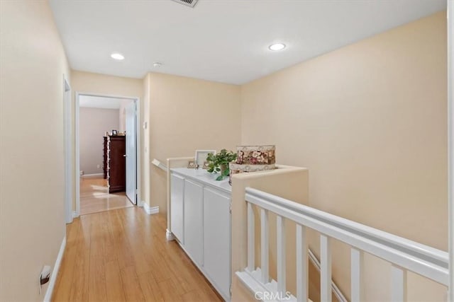 hallway featuring baseboards, recessed lighting, an upstairs landing, and light wood-style floors