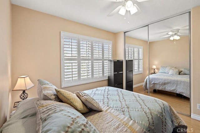 bedroom featuring baseboards, a closet, a ceiling fan, and light wood-style floors