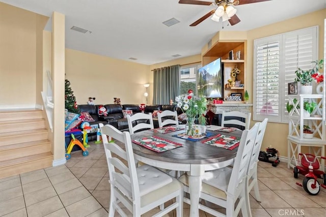 dining area featuring light tile patterned floors, stairs, visible vents, and a ceiling fan