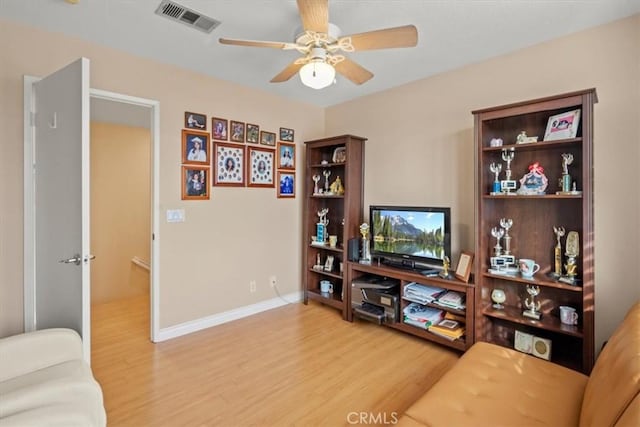 living area featuring ceiling fan, wood finished floors, visible vents, and baseboards