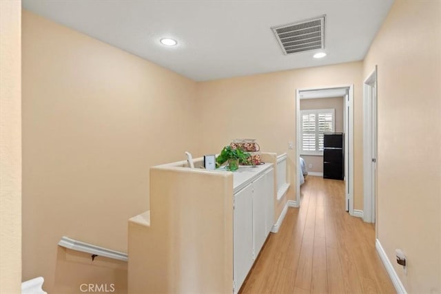 hallway featuring light wood-type flooring, visible vents, baseboards, and recessed lighting