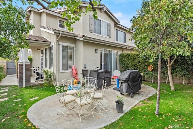 back of house featuring a patio area, fence, a lawn, and stucco siding