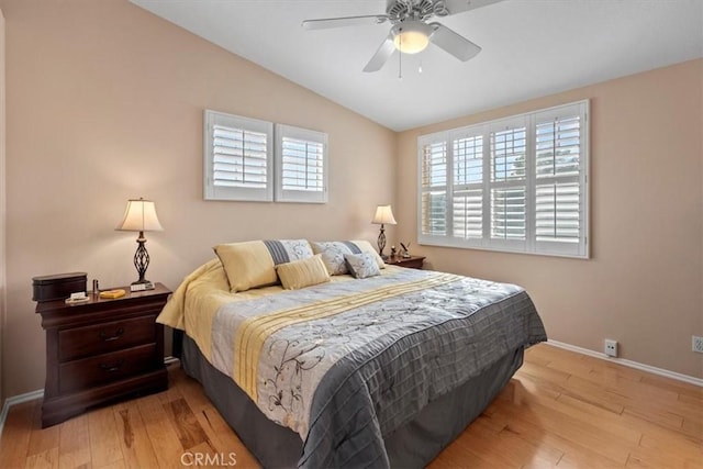 bedroom with vaulted ceiling, light wood-type flooring, a ceiling fan, and baseboards