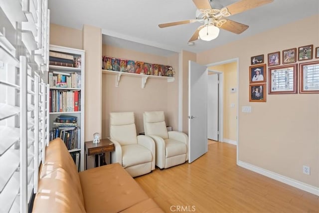 living area with ceiling fan, wood finished floors, and baseboards