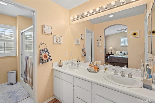 full bath featuring double vanity, ceiling fan, a sink, and ensuite bathroom