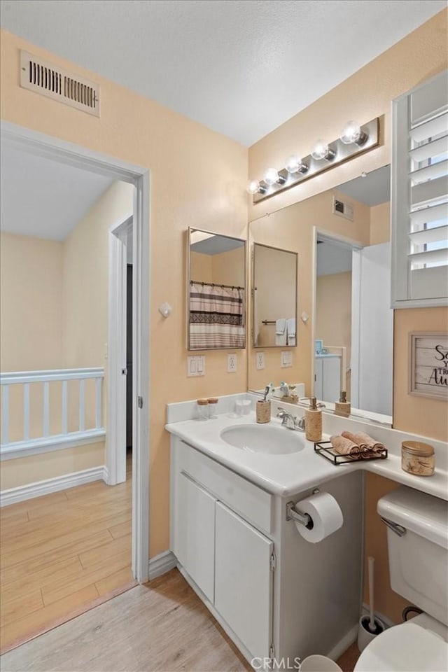 bathroom featuring toilet, visible vents, wood finished floors, and vanity