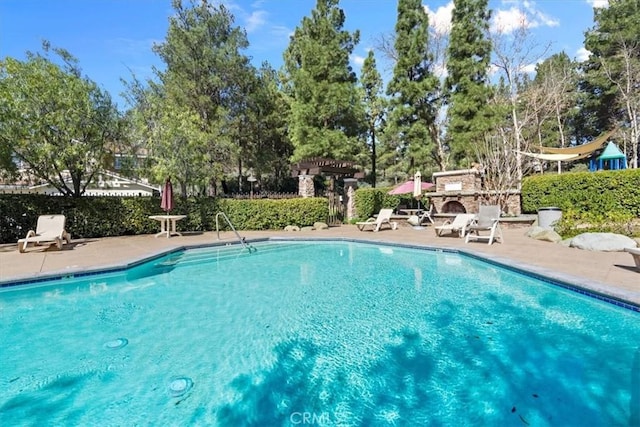 community pool with a patio area, fence, and a pergola