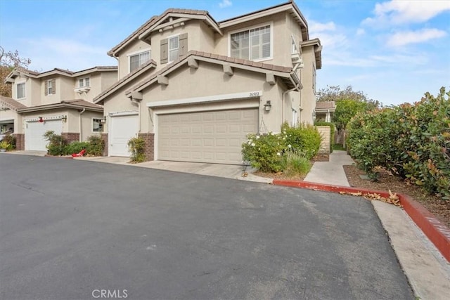 view of front of home featuring a tile roof, driveway, an attached garage, and stucco siding