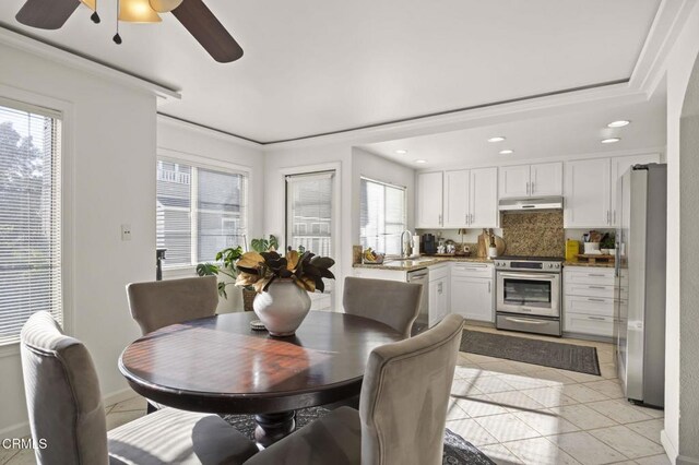 tiled dining space featuring ceiling fan, sink, and ornamental molding