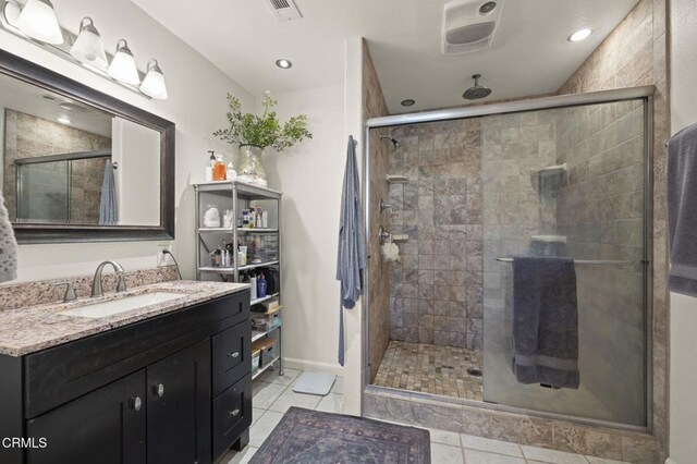 bathroom with a shower with shower door, vanity, and tile patterned flooring