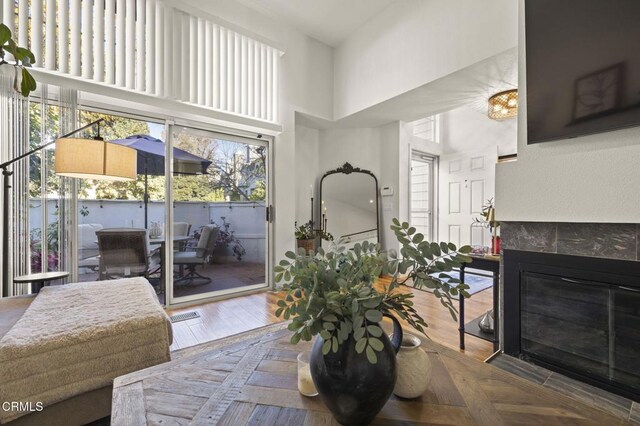 living room featuring hardwood / wood-style flooring, a high ceiling, and a fireplace