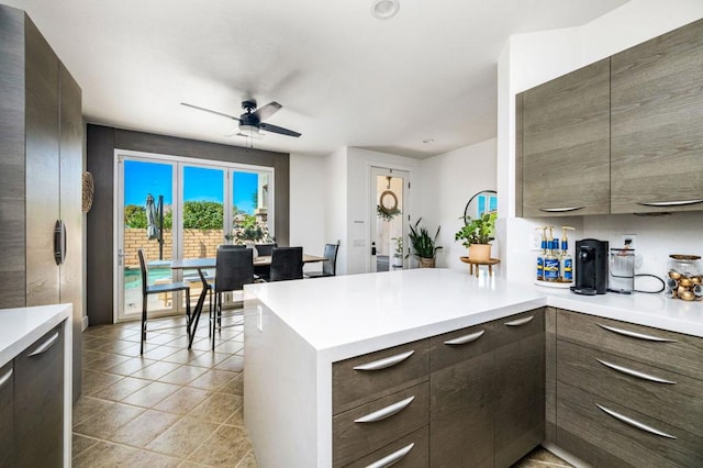 kitchen with ceiling fan, kitchen peninsula, and dark brown cabinetry