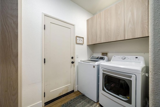 washroom featuring dark hardwood / wood-style floors, independent washer and dryer, and cabinets