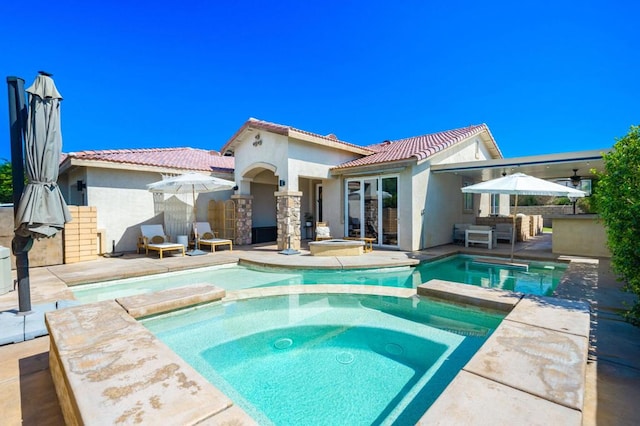 rear view of property with a swimming pool with hot tub, a patio area, and area for grilling