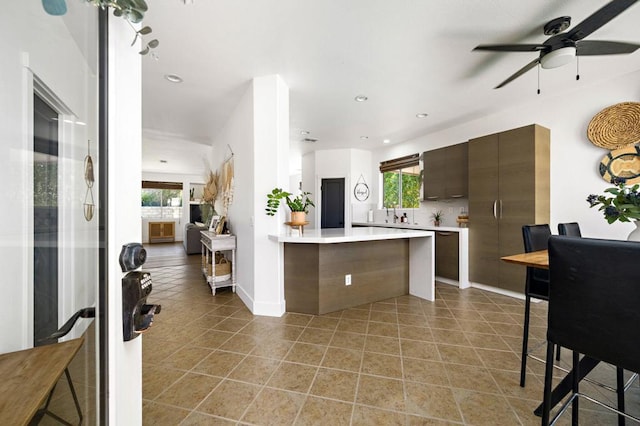 kitchen with ceiling fan, decorative backsplash, dark brown cabinets, and tile patterned floors