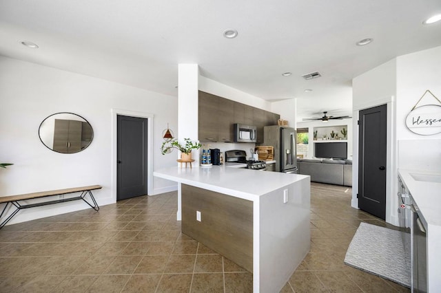 kitchen featuring ceiling fan, dark tile patterned flooring, kitchen peninsula, appliances with stainless steel finishes, and dark brown cabinets