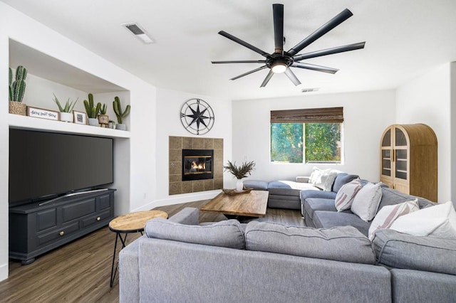 living room featuring ceiling fan, dark hardwood / wood-style floors, built in features, and a tiled fireplace