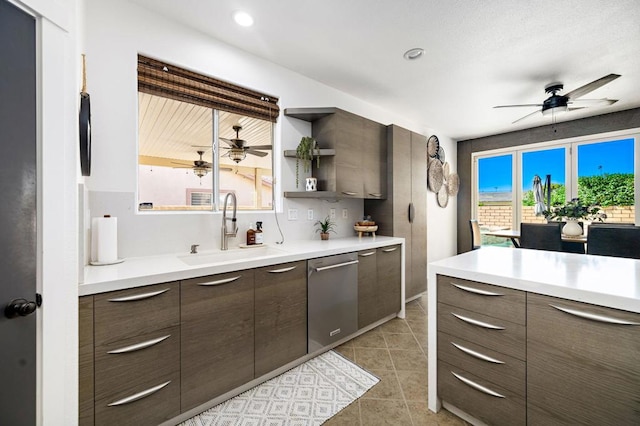 kitchen featuring sink, dark brown cabinetry, stainless steel dishwasher, and light tile patterned flooring